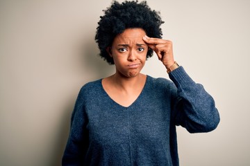 Young beautiful African American afro woman with curly hair wearing casual sweater worried and stressed about a problem with hand on forehead, nervous and anxious for crisis