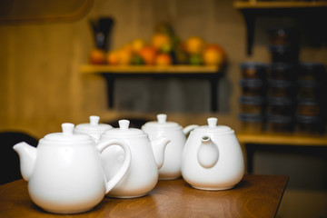 Teapots with black tea on a wooden table in a cafe. White small teapots.