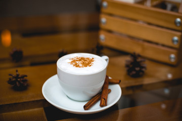 White, small mug of aromatic coffee with cinnamon on a table in a restaurant. Beautiful serving of the drink.