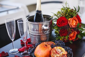 Cold champagne with fruits and flowers on the table of a yacht. Romantic evening for two.