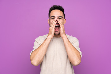 Young handsome man over isolated purple background shouting and announcing something