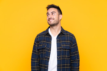 Young handsome man over isolated yellow background laughing and looking up