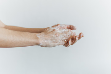 Fototapeta premium Detalhe de mãos femininas com espuma de sabonete. Lavar as mãos para combater o coronavírus.