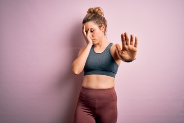 Young beautiful blonde sportswoman doing sport wearing sportswear over pink background covering eyes with hands and doing stop gesture with sad and fear expression. Embarrassed and negative concept.