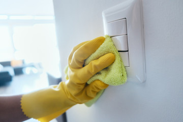 Person With Gloves Disinfecting Light Switches Using Sanitizer