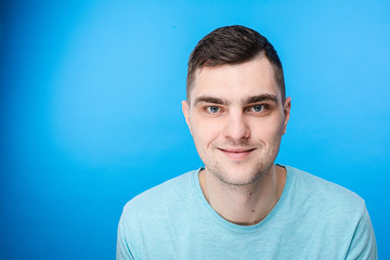 Portrait of young caucasian male with short dark hair and pretty face is happy