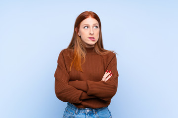 Fototapeta premium Young redhead woman over isolated blue background with confuse face expression