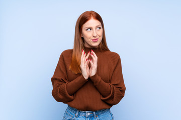 Young redhead woman over isolated blue background scheming something