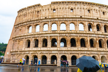 Fototapeta na wymiar Rome, Italy. Ancient Roman Colosseum, a popular European city amphitheater landmark and tourist attraction with tourists/ people sightseeing. Historic vintage architecture ruins on rainy day.