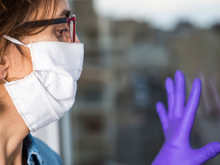 Woman with face mask and gloves quarantining at home.