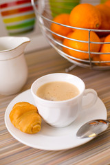 A mug of black coffee with fresh French croissant. Healthy breakfast.