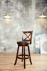 Wooden bar stool and stucco wall background, front view