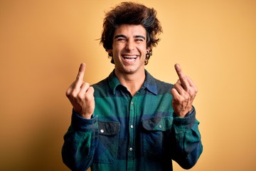 Young handsome man wearing casual shirt standing over isolated yellow background Showing middle...