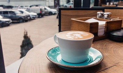 Soft focus on latte coffee cup. Hot milk art coffee on wooden table in cafe.