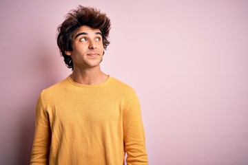 Fototapeta na wymiar Young handsome man wearing yellow casual t-shirt standing over isolated pink background smiling looking to the side and staring away thinking.
