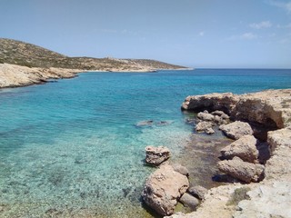 A rocky bay, with a shingle beach on the beautiful Greek island of Donousa.  Crystal clear blue waters invite you to cool off and swim.