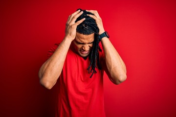 Young handsome african american afro man with dreadlocks wearing red casual t-shirt suffering from...