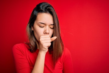 Young beautiful brunette girl wearing casual t-shirt over isolated red background feeling unwell and coughing as symptom for cold or bronchitis. Health care concept.