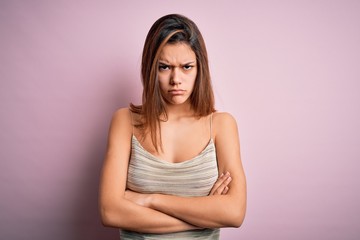Young beautiful brunette girl wearing casual striped t-shirt over isolated pink background skeptic and nervous, disapproving expression on face with crossed arms. Negative person.
