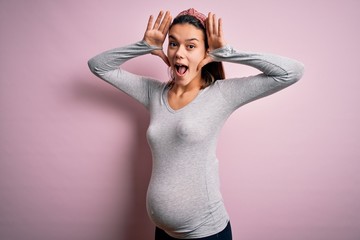 Young beautiful teenager girl pregnant expecting baby over isolated pink background Smiling...