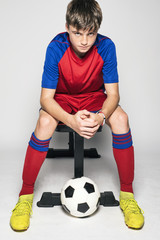 Male youth soccer player sitting on bench ready to play