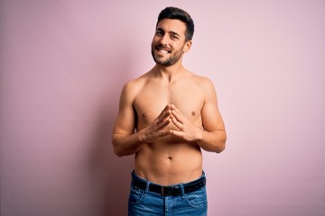 Young handsome strong man with beard shirtless standing over isolated pink background Hands together and fingers crossed smiling relaxed and cheerful. Success and optimistic