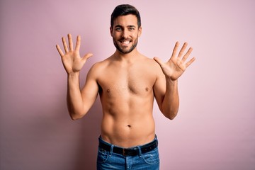 Fototapeta premium Young handsome strong man with beard shirtless standing over isolated pink background showing and pointing up with fingers number ten while smiling confident and happy.
