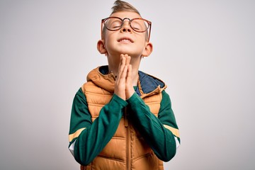 Young little caucasian kid with blue eyes wearing winter coat and smart glasses begging and praying...