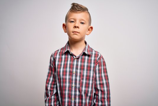 Young little caucasian kid with blue eyes wearing elegant shirt standing over isolated background Relaxed with serious expression on face. Simple and natural looking at the camera.