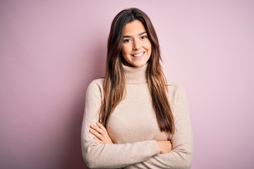 Obraz premium Young beautiful girl wearing casual turtleneck sweater standing over isolated pink background happy face smiling with crossed arms looking at the camera. Positive person.