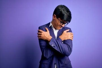 Young handsome business man wearing jacket and glasses over isolated purple background Hugging oneself happy and positive, smiling confident. Self love and self care