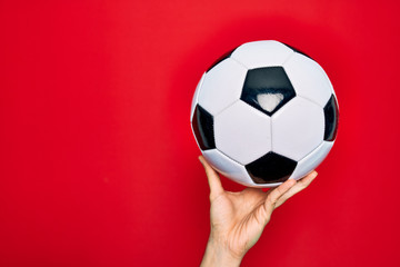 Beautiful hand of man holding football ball over isolated red background