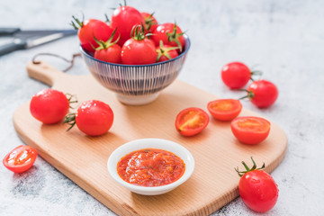 Cherry tomatoes and a spoonful of ketchup on a cutting board