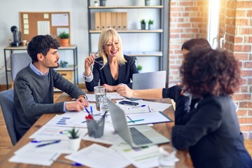 Group of business workers smiling happy and confident. Working together with smile on face  using laptop and speaking at the office
