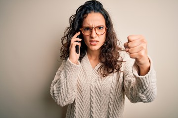 Young beautiful woman with curly hair having conversation talking on the smartphone annoyed and frustrated shouting with anger, crazy and yelling with raised hand, anger concept
