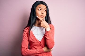 Young beautiful chinese woman wearing casual sweater over isolated pink background Thinking worried about a question, concerned and nervous with hand on chin