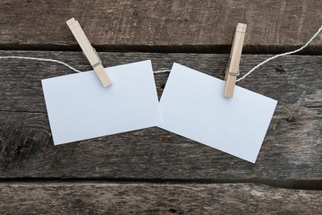 Two white note cards pinned to a string on a rustic wooden background