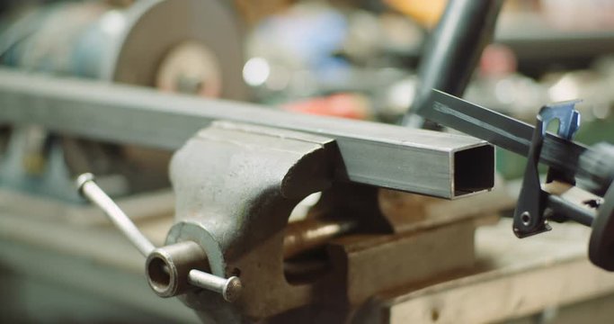 industry worker metal part with electric hacksaw