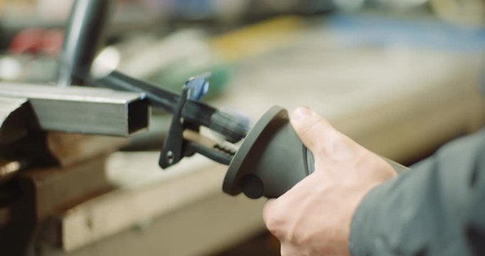 industry worker metal part with electric hacksaw