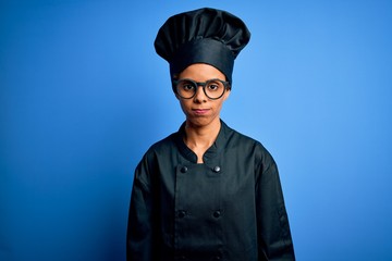Young african american chef woman wearing cooker uniform and hat over blue background depressed and worry for distress, crying angry and afraid. Sad expression.