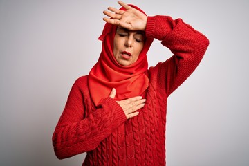 Middle age brunette woman wearing muslim traditional hijab over isolated white background Touching forehead for illness and fever, flu and cold, virus sick