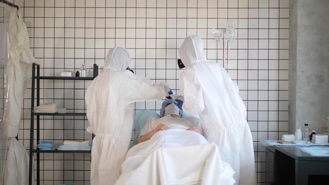 Doctor in Hazmat Sterile Suit measuring temperature of a patient in a hospital.