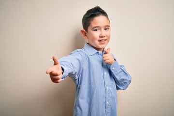 Young little boy kid wearing elegant shirt standing over isolated background pointing fingers to camera with happy and funny face. Good energy and vibes.