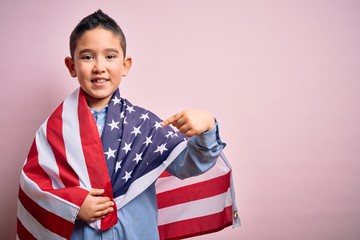 Young little patriotic boy kid covered on united states of america flag on independence day with surprise face pointing finger to himself