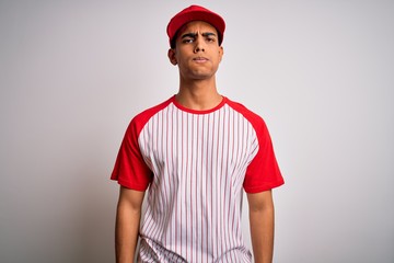 Young handsome african american sportsman wearing striped baseball t-shirt and cap puffing cheeks with funny face. Mouth inflated with air, crazy expression.