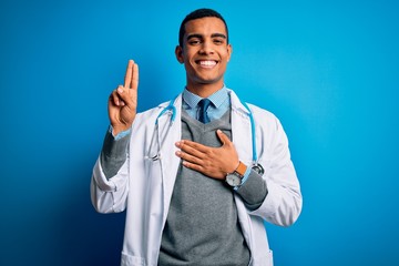 Handsome african american doctor man wearing coat and stethoscope over blue background smiling swearing with hand on chest and fingers up, making a loyalty promise oath