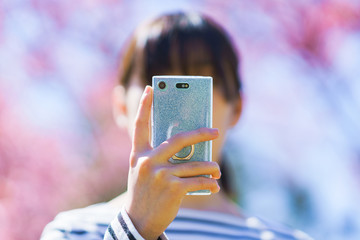 Japanese girl take photo for sharing SNS by using smart phone in Japan