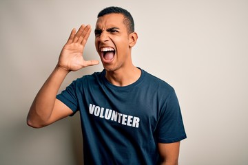 Young handsome african american man volunteering wearing t-shirt with volunteer message shouting and screaming loud to side with hand on mouth. Communication concept.