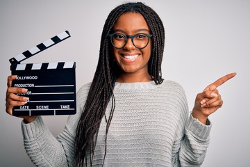 Young african american director girl filming a movie using clapboard over isolated background very...