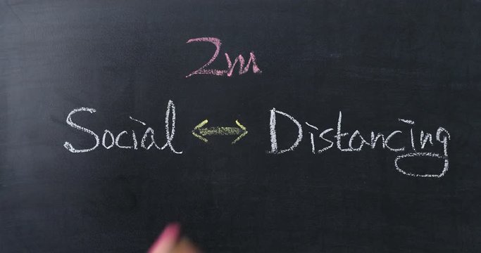 Hand writing 2m on Double-headed arrow between social and distancing on blackboard